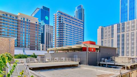 Flat concrete roof on top of a downtown building surrounded by taller buildings.
