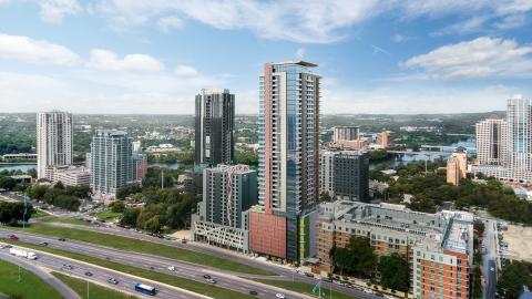 Rendering of a row of medium-height and tall urban buildings that overlook an interstate highway. 