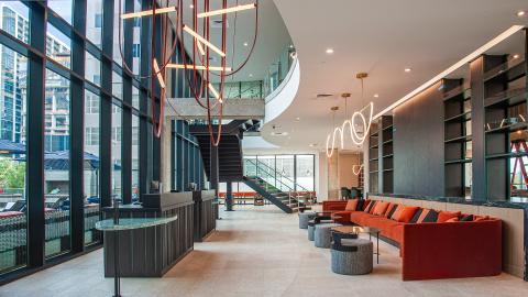 Two-story modern hotel lobby with a wall of windows and a swooping overhang.