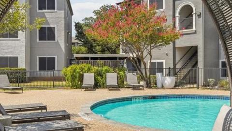 Photo of a traditional 3-story apartment complex viewed from a poolside cabana.