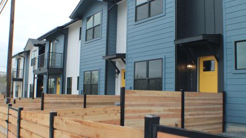 Picture of six two-story rowhouse-style contemporary homes with small fenced backyards.