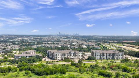 Photo of a suburban apartment village in a master-planned community with tall downtown buildings in the distance.